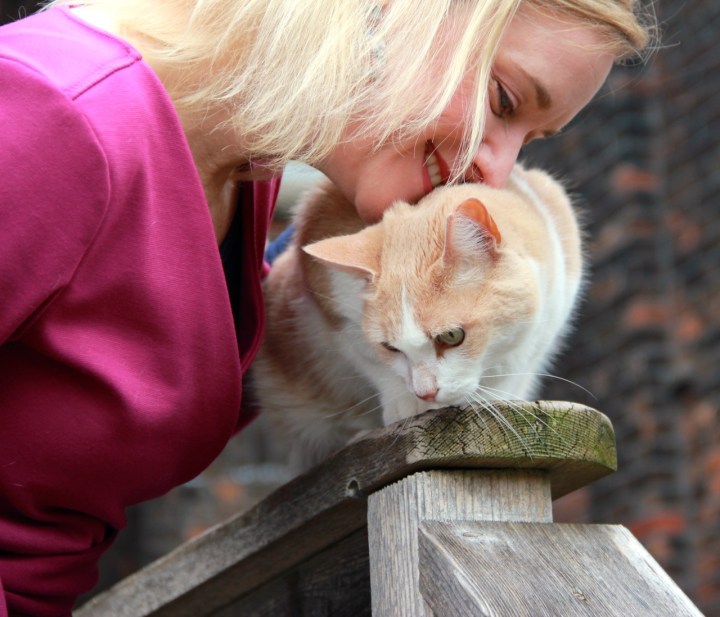 Close up of Lori snuggling her cat on the porch bannister